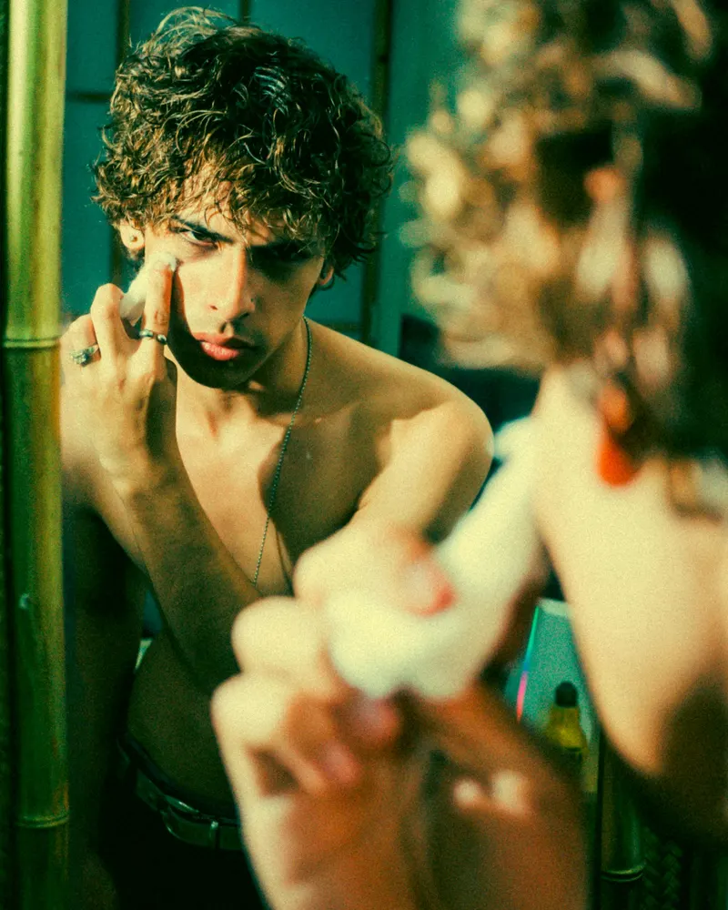 Un homme touche sa joue devant un miroir.
